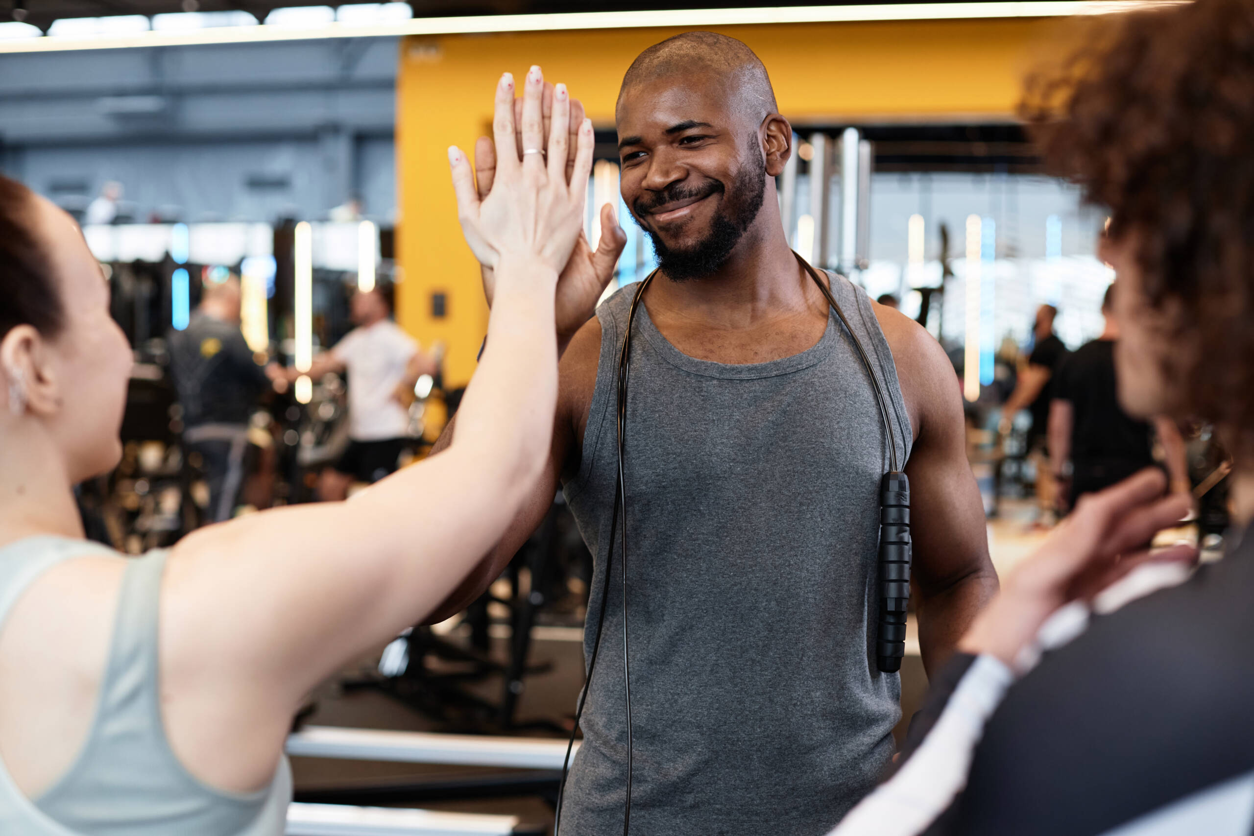Smiling Black Fitness Coach High Five with Client Waist up portrait of smiling Black fitness coach high five with client meeting for training in gym